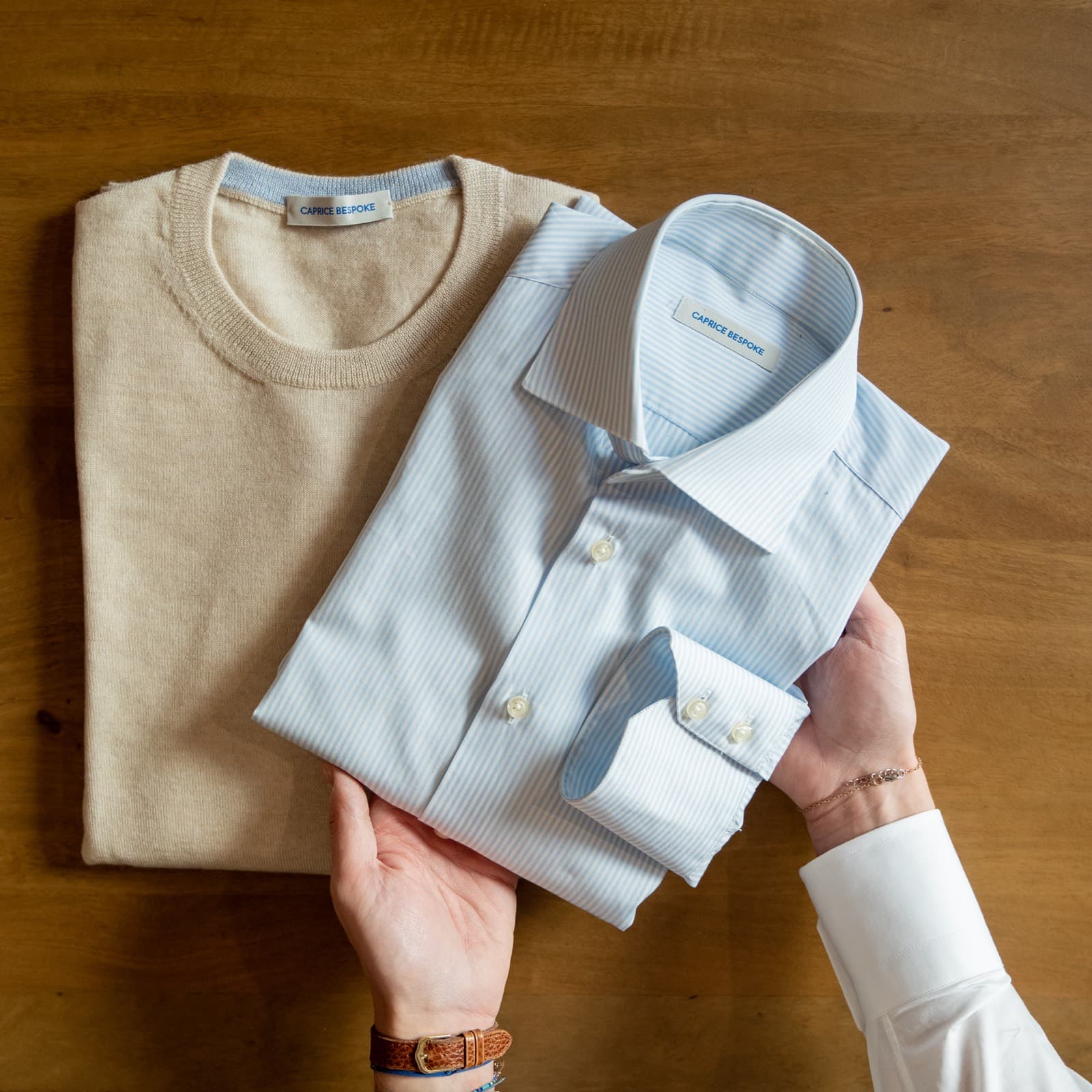 Hands folding a crisp shirt and knit: a wardrobe that finally fits.